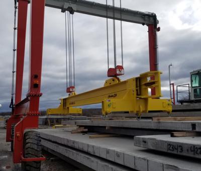 Gantry crane lifting system lifting a yellow spreader beam.