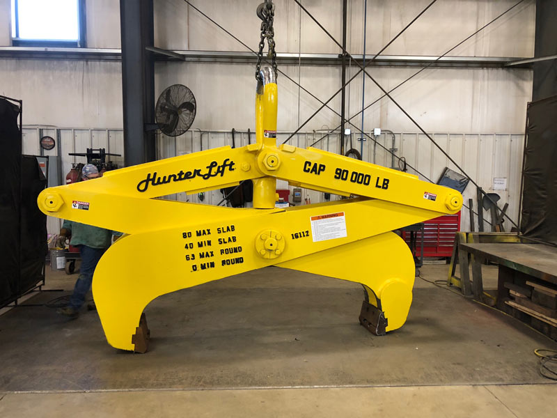 Yellow repaired below the hook auto slab tong crane attachment. 